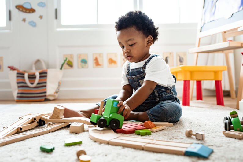 Little boy playing with a railroad train toy