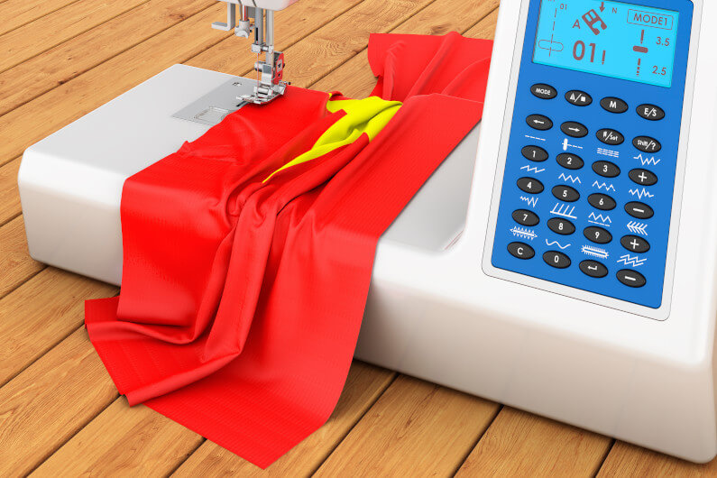 Modern sewing machine with Vietnamese flag on the wooden table.